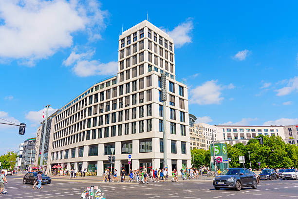 Berlin, Germany - August 16, 2025: Contemporary building design in Berlin's Leipziger Platz, featuring striking geometric shapes and large glass surfaces, under a vibrant blue sky.