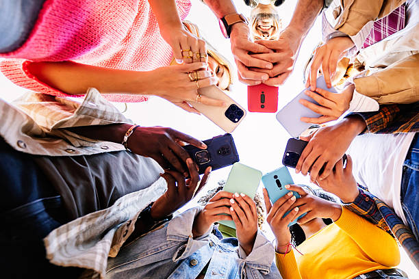 istock Young group of student people using smart phones together outside 2234645670