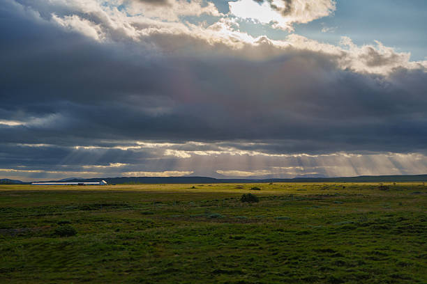 Sunbeams illuminating the lush green icelandic plains beneath a dramatic cloudy sky, creating a breathtaking natural spectacle filled with tranquility and beauty in nature