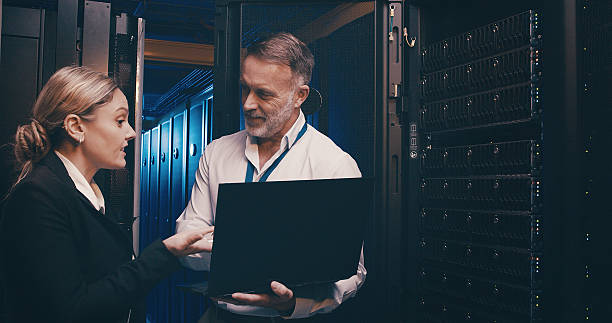 istock Server room, online and people on laptop for network maintenance, IT support and database. Talking, technician team and man with woman on computer for diagnostics, system update and cybersecurity 2234648711