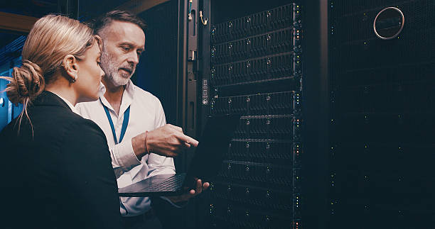 istock Cybersecurity, laptop and upgrade with people in server room together for network administration. Collaboration, computer and storage with tech support team in data center for firewall installation 2234648727