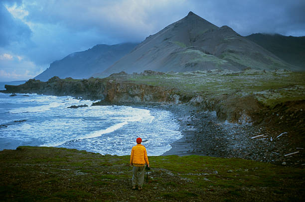 Serene view of man  looking at epic seaside landscape in Iceland, shot on camera film during experiential Golden Circle road trip