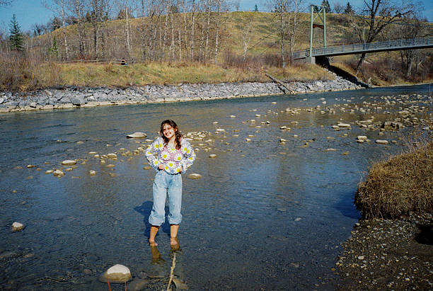 Cheerful woman standing in the river on first days of summer,shot on camera film with vintage vibe