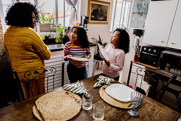 istock Mother and daughters setting the table in the kitchen at home 2234656206