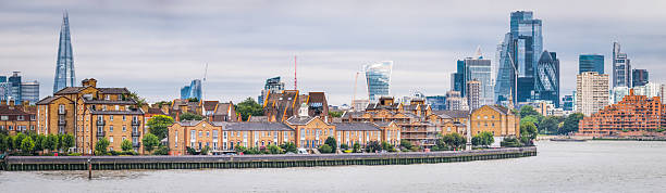 Panoramic view along the River Thames from Canary Wharf to the homes in Rotherhithe and Limehouse overlooked by the skyscrapers of the City of London, UK.
