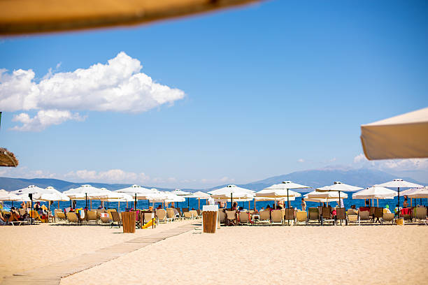 Tourists are relaxing on a sunny beach with umbrellas and deck chairs