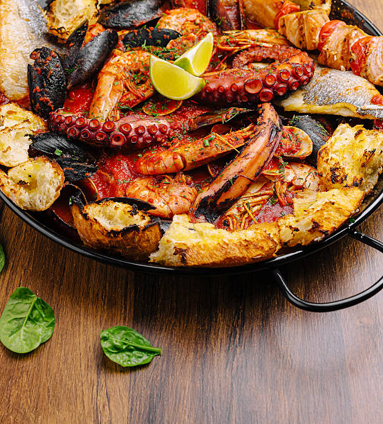 istock Seafood plate with octopus, shrimp, fish, and lime on wood table 2234659208