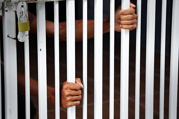 istock Hands Grasping Metal Bars of a Gate Symbolizing Confinement and Restriction 2234659314