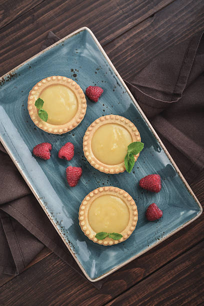 Mini tarts with  lemon and custard  filling on wooden rustic board top view