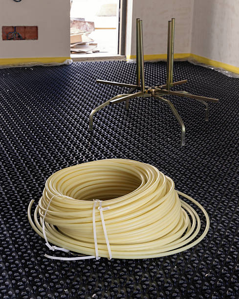 istock Roll with pipes placed over black insulation sheets. Underfloor heating system in a new building 2234670426