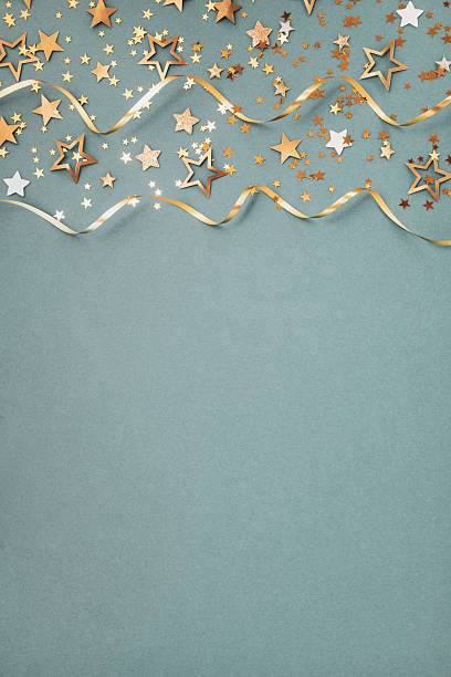New Year, Christmas or birthday festive background top view. Celebration composition with golden confetti stars and serpentine party streamers.