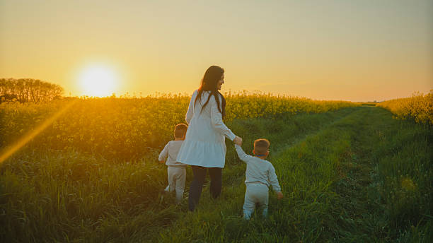 istock Mother Walking with her Two Sons at Sunset in a Field 2234675329