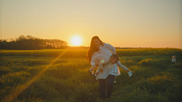 istock Mother Playing with her Children in a Field at Sunset 2234675331