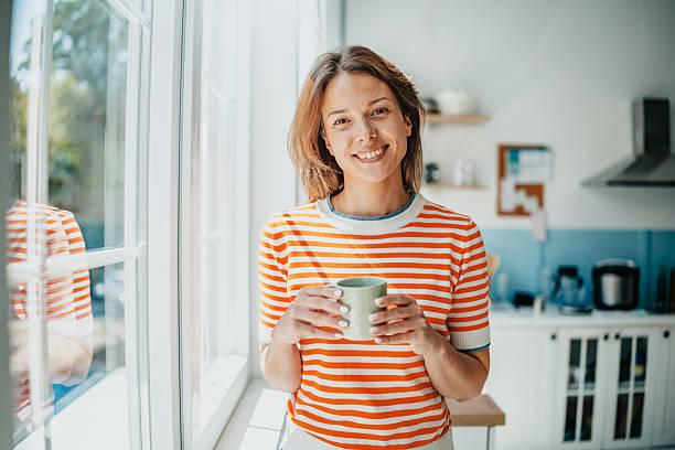 istock Woman enjoying a warm beverage while smiling in a bright domestic kitchen with natural light 2234676232