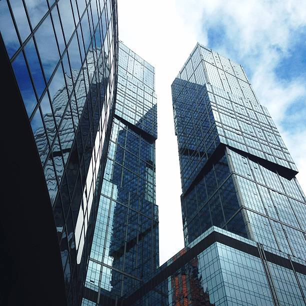 Skyscrapers with glass facades reflect the blue sky and white clouds in Moscow, near Afimall. The buildings are characterized by modern architecture, featuring sleek, vertical lines and multiple rectangular windows. These high-rise structures create an imposing urban landscape, emphasizing the city's emphasis on contemporary design and commercial development. The reflective surfaces add a dynamic visual element, capturing the surrounding environment and changing light patterns throughout the day.