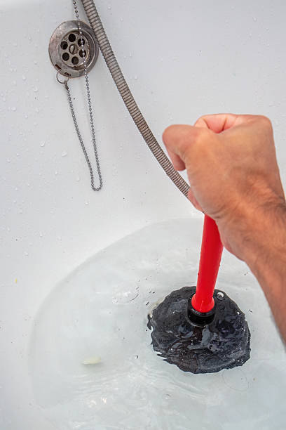 istock Homeowner unclogging bathtub drain with a plunger 2234677582