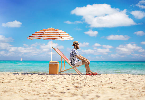 Man sitting by the sea on a sandy beach under umbrella