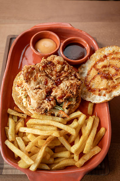 istock Delicious fried chicken sandwich with golden fries served in a rustic setting 2234689150