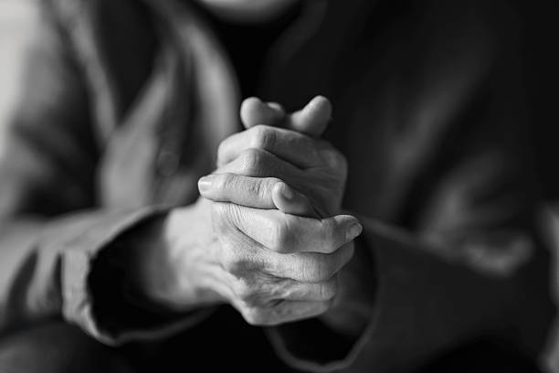 closeup of the hands of a old caucasian woman with his hands clasped, in black and white photograph