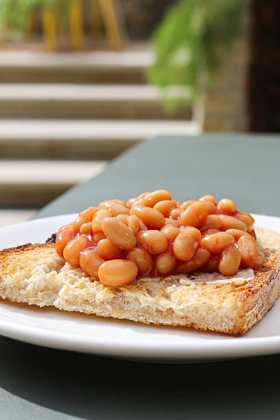 Image of eating baked beans on toast breakfast plate, protein-rich meal with tomato sauce, processed food concept