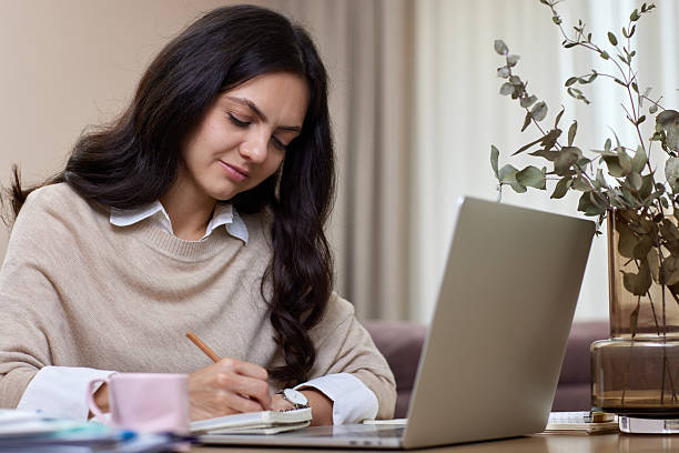 istock woman using laptop while working remotely from home in living room 2234694881