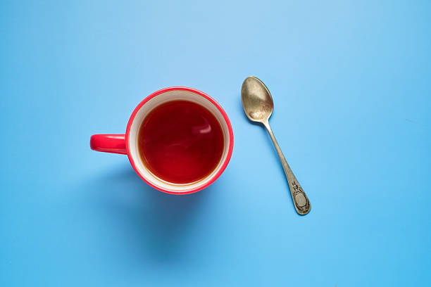 istock Brightly colored cup full of tea next to a spoon and blue background 2234696719