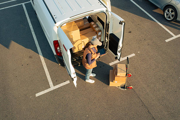 istock Female delivery worker dropping off parcels via trolley cart. 2234697052