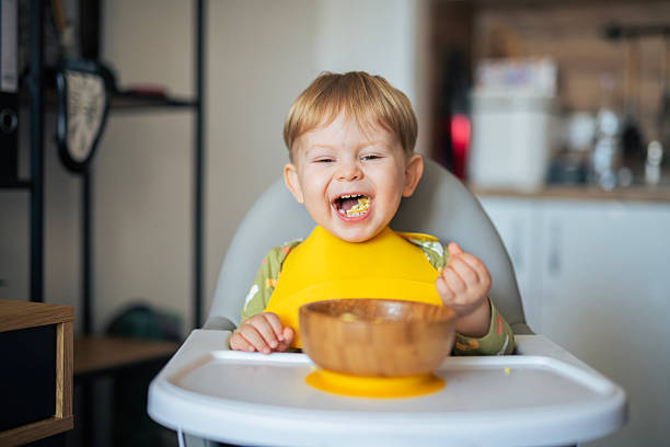 istock Cute boy feeding himself breakfast at home. 2234697512