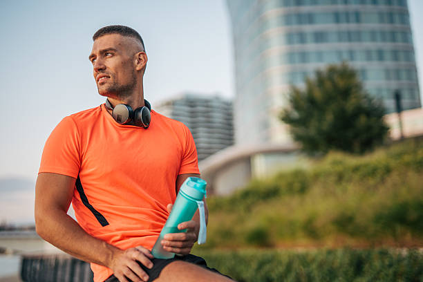 istock Young sportsman resting after training session outdoors, holding water bottle 2234704194