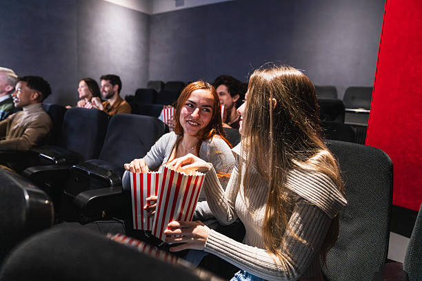 istock Young women sharing popcorn while watching movie in cinema 2234706931