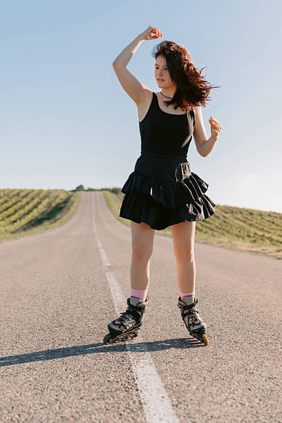 istock Young woman roller skating on empty rural road, active lifestyle 2234707692