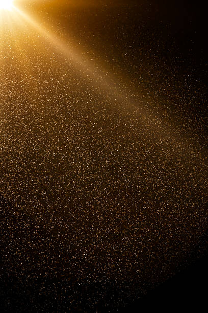 istock Golden particles falling from bright light beam on black background 2234708141