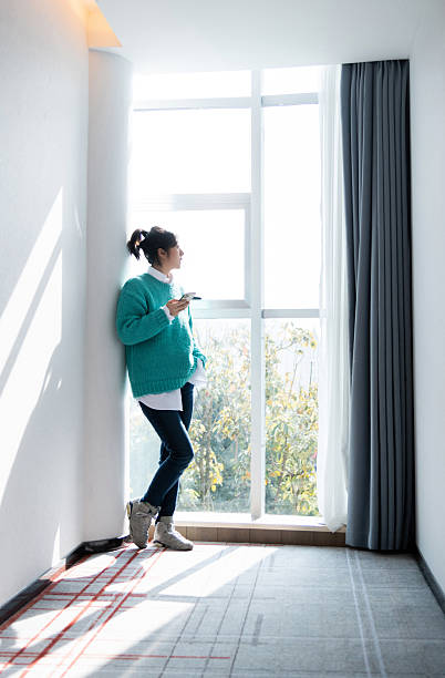 istock Woman standing next to window and using mobile phone 2234708550