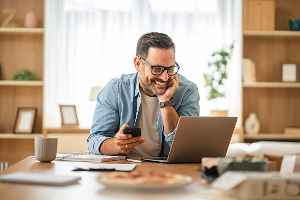 istock Happy entrepreneur working from home using laptop and smart phone 2234709967