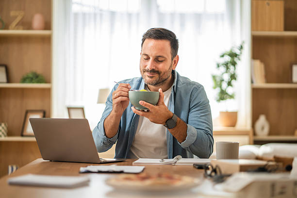 istock Happy entrepreneur enjoying healthy lunch while working remotely from home office 2234710589