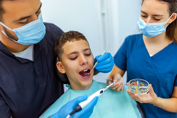 istock Two Dentists Treating Boy's Teeth with Drill Extension in Clinic 2234712517