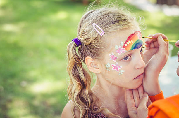 little lovely girl waiting for rainbow face painting to be done