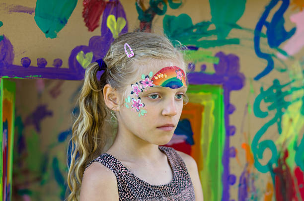 little lovely girl waiting with rainbow face painting