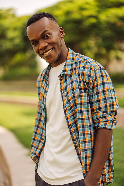 istock Smiling man wearing a plaid shirt standing outdoors in a sunny park 2234714163
