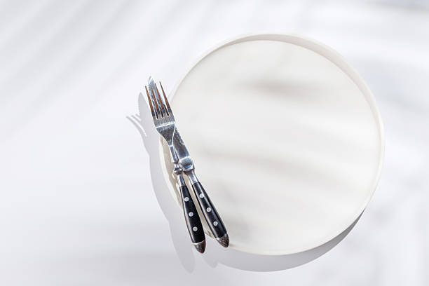 Empty plate on a white background with leaf shadows, perfect food mockup. Flat lay with copy space