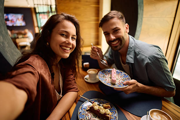 istock Happy couple taking selfie while enjoying in dessert in a cafe and looking at camera. 2234718182