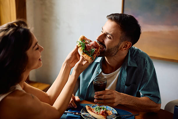 istock Young man being fed with by his girlfriend with a pizza. 2234718586