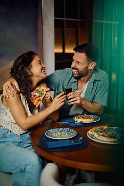 istock Cheerful couple toasting while eating pizza in restaurant. 2234718626