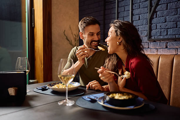istock Happy man feeding his girlfriend during their lunch in a restaurant. 2234720389