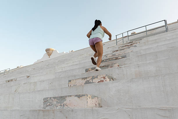 istock Athletic woman climbing stadium bleachers, powering through challenging workout, strengthening muscles under radiant sunlight with expansive sky backdrop 2234725815