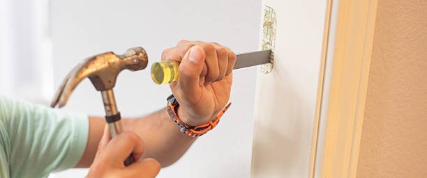 Panorama view handyman carves marked hinge recess on white door frame using hammer delivers measured strikes and chisel. Wood chips scatter as shaping smoothing begins. DIY home repair in Texas