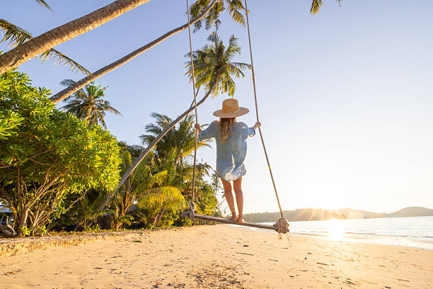 istock Female standing on beach swing at sunset 2234730304