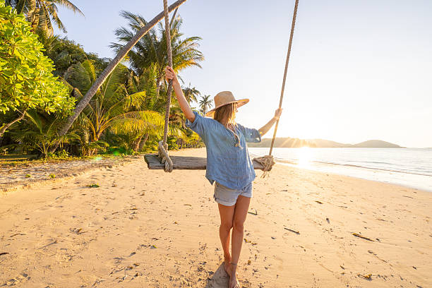 istock Woman Enjoying Swing on Tropical Beach Sunset 2234730590