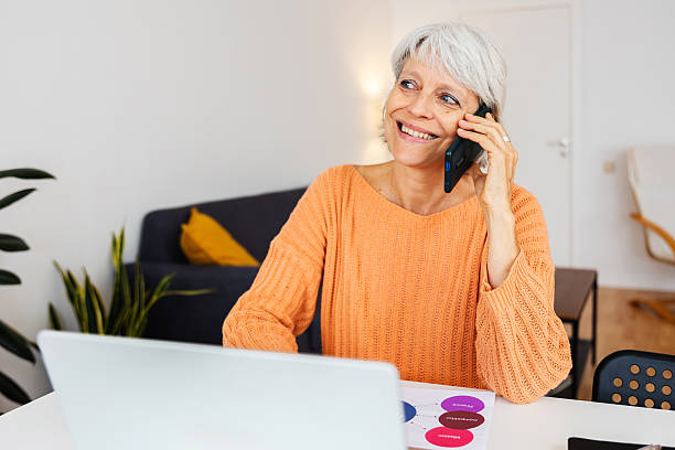 istock Senior businesswoman talking on phone while working on laptop at home 2234733091