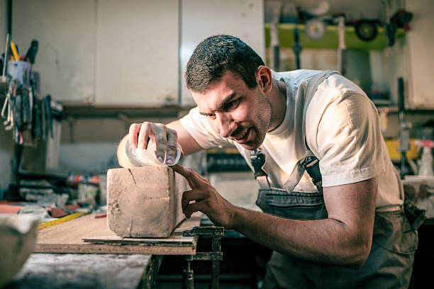 istock Focused Carpenter Smoothing Wooden Block in Workshop Environment 2234735417